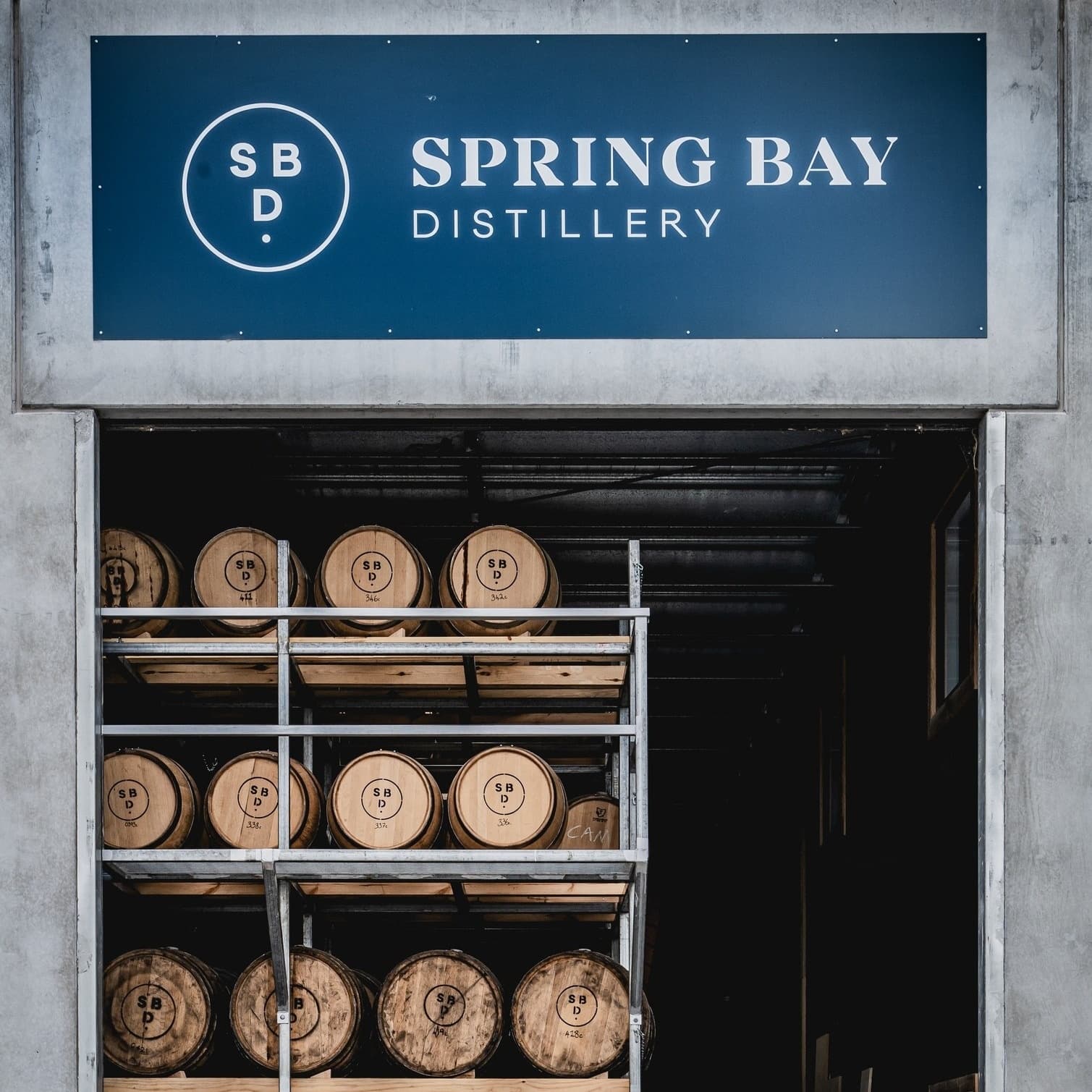 Spring Bay Distillery entrance with stacked oak barrels in racks
