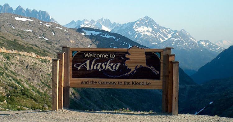 Welcome to Alaska sign at mountain pass showcasing wilderness