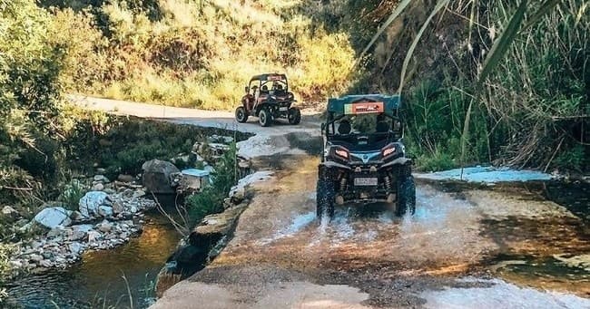 UTV crossing shallow stream through forested trail, adventure