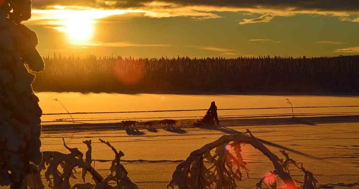 Sunset over frozen lake in Lapland with skier silhouette