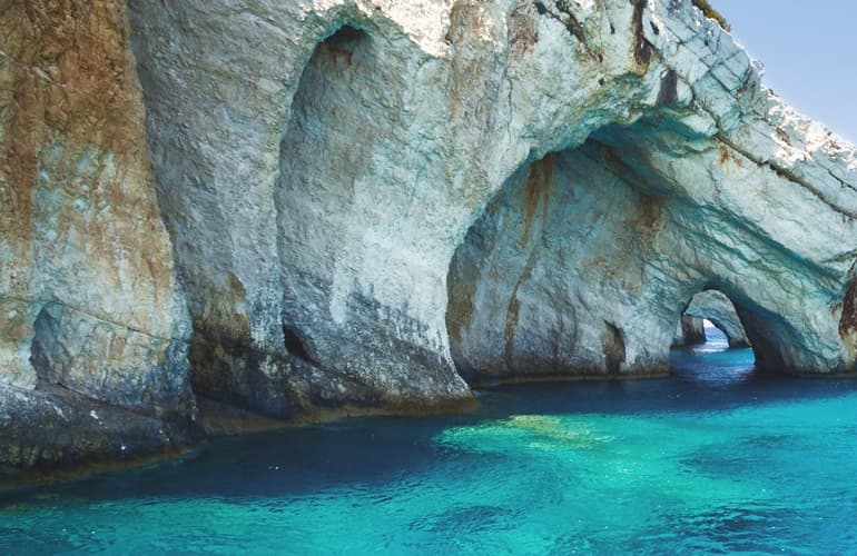 Blue sea cave with archways and clear water, boating exploration