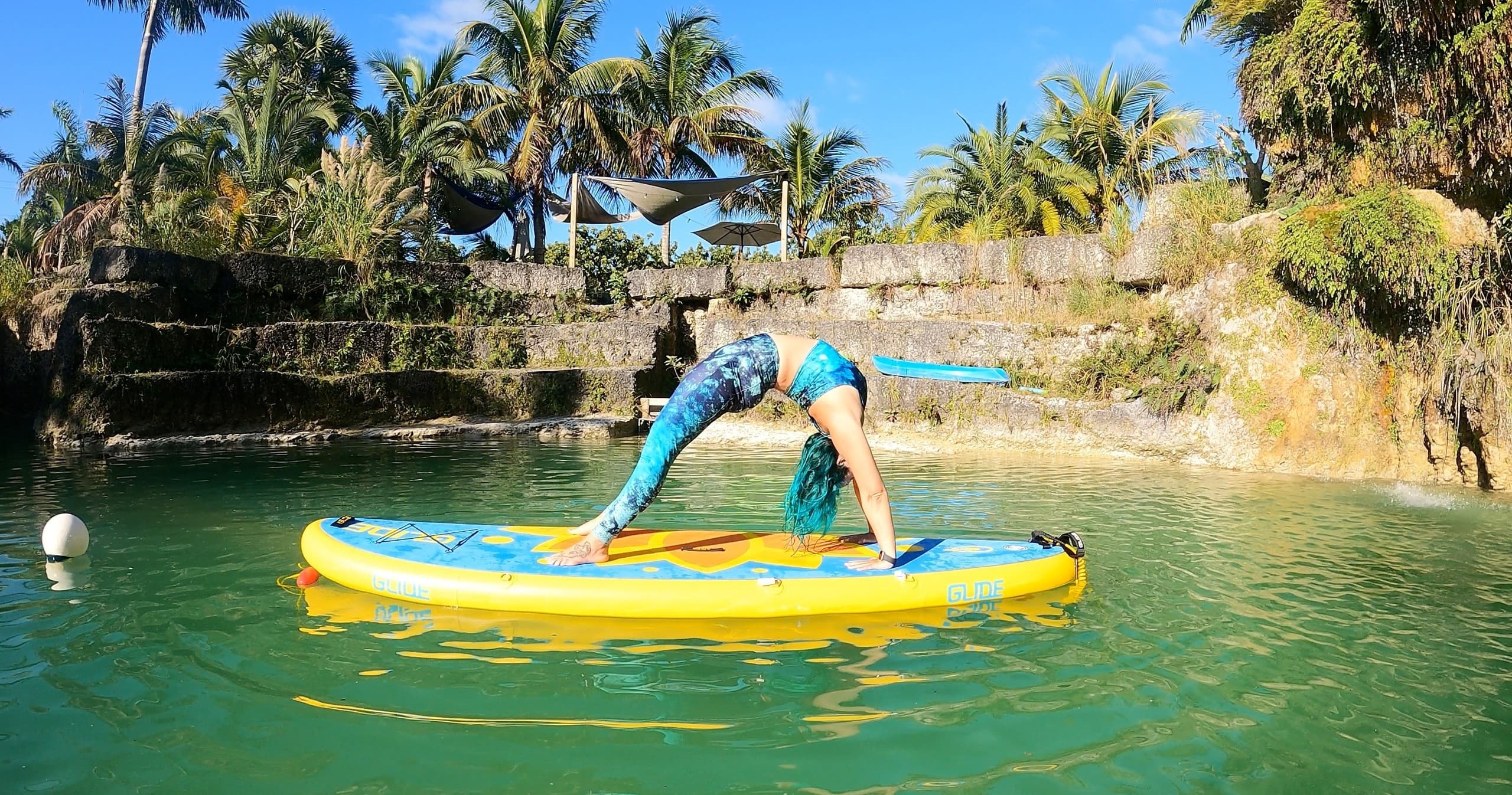 Paddleboard yoga on a tropical lagoon with palm-tree shore