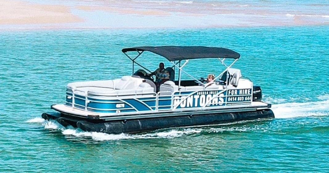 Pontoon boat cruising turquoise inlet waters near sandy coast