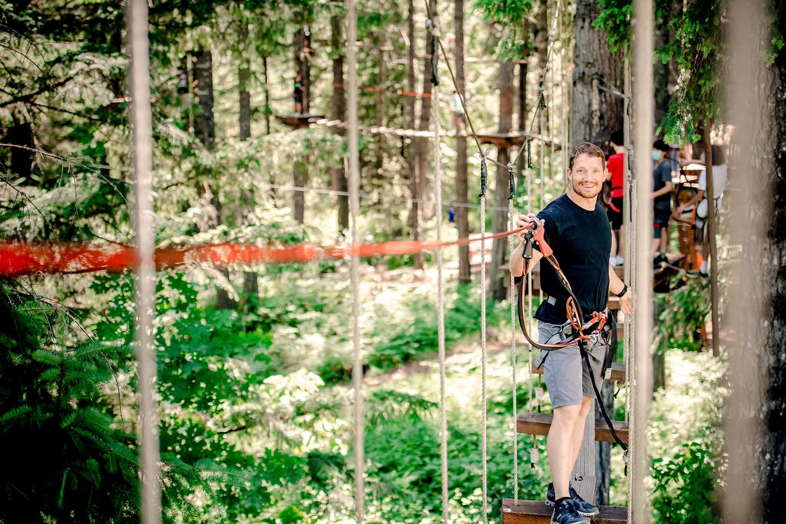 Participant navigating elevated ropes course in wooded park