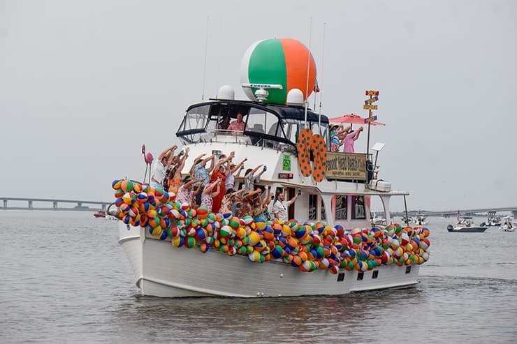 Festive boat covered in balloons with passengers celebrating at sea