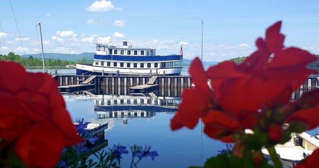 Classic paddle-style lakeboat docked with flowers and calm harbor
