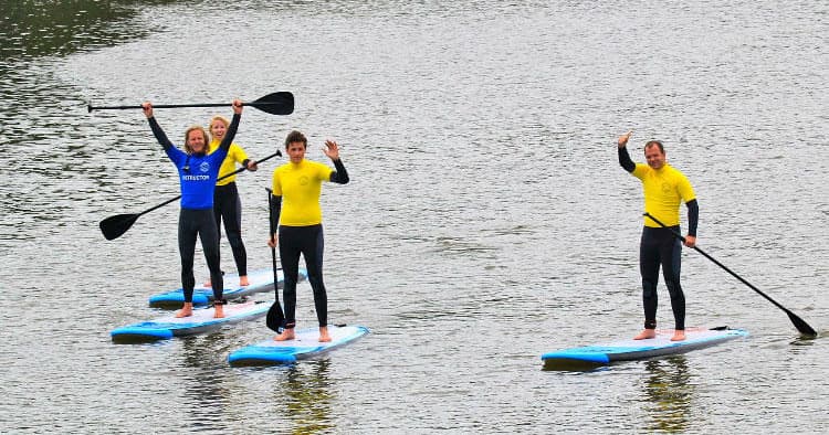 Stand-up paddleboarders cruising calm river water near shore