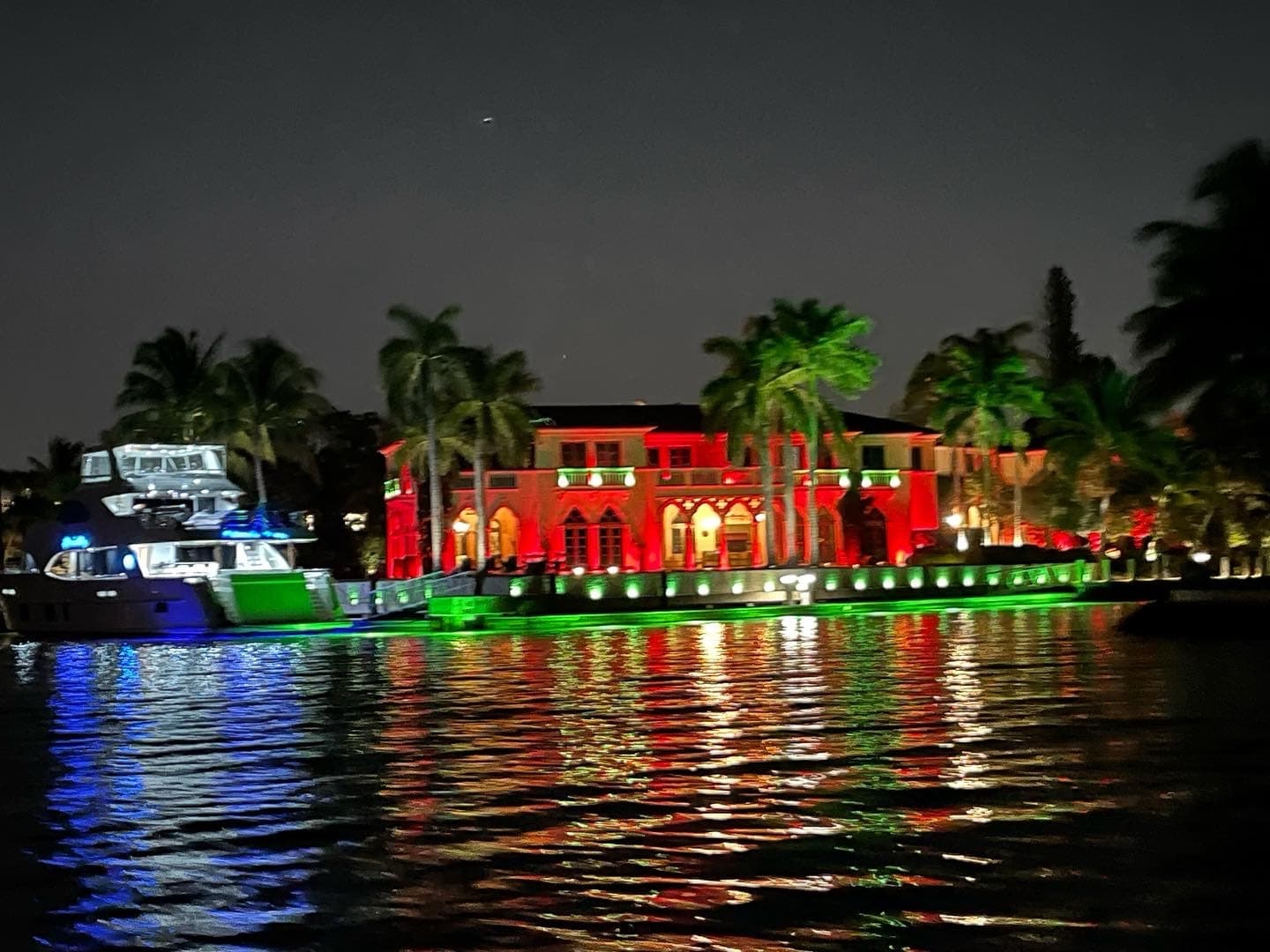 Nighttime waterfront with illuminated mansion reflecting on water