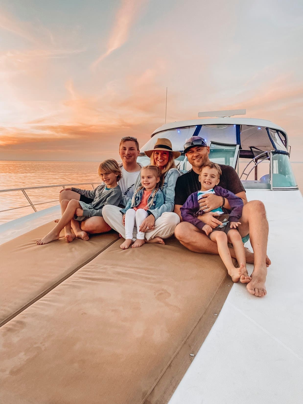 Family relaxing on yacht deck at golden sunset on sea