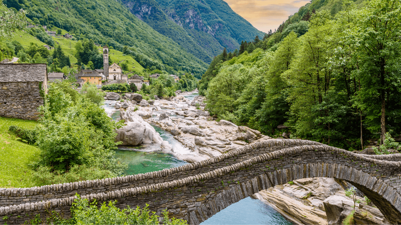 Ancient stone bridge over rushing river in green alpine valley