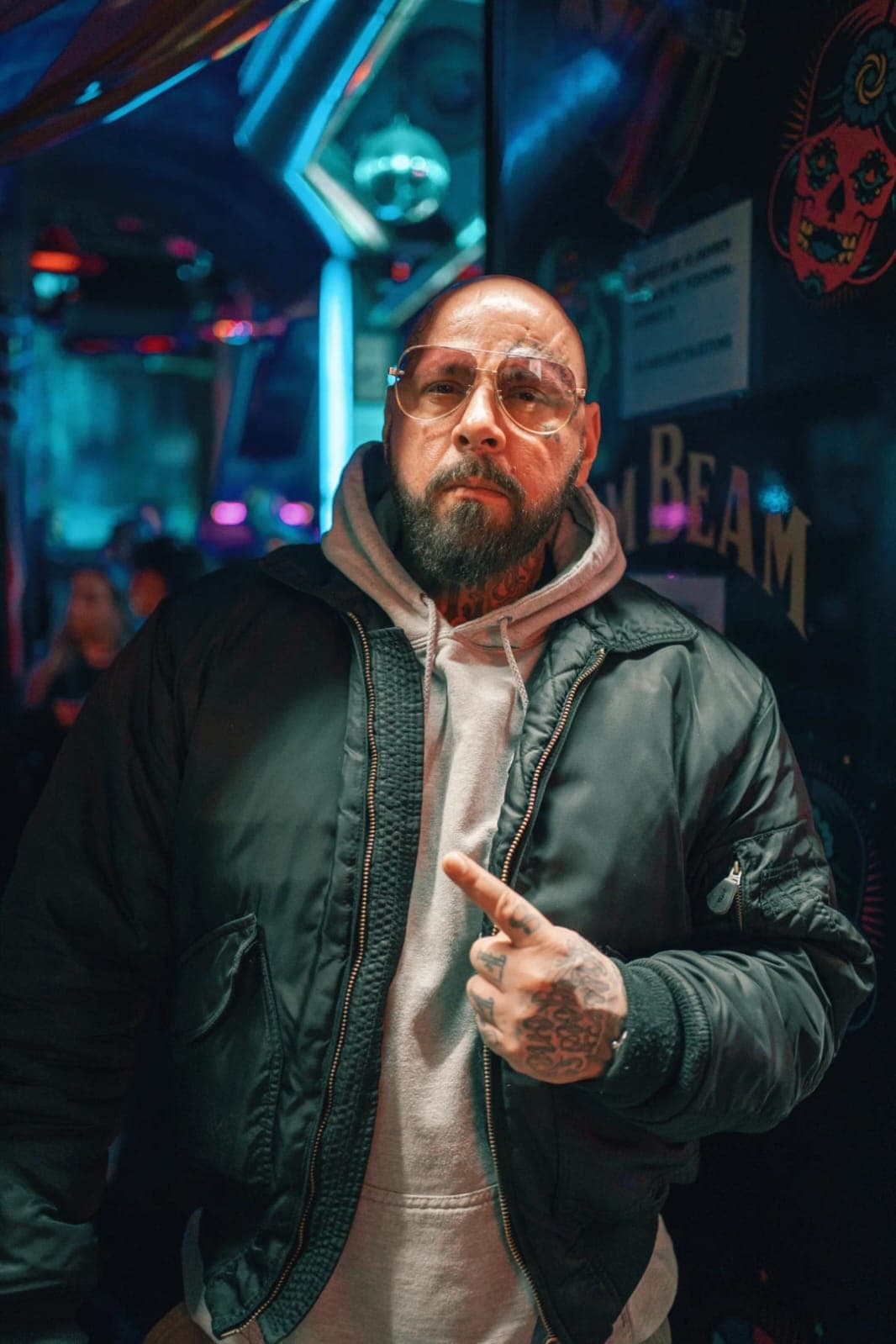 Portrait of bearded man in hooded jacket at neon-lit arcade