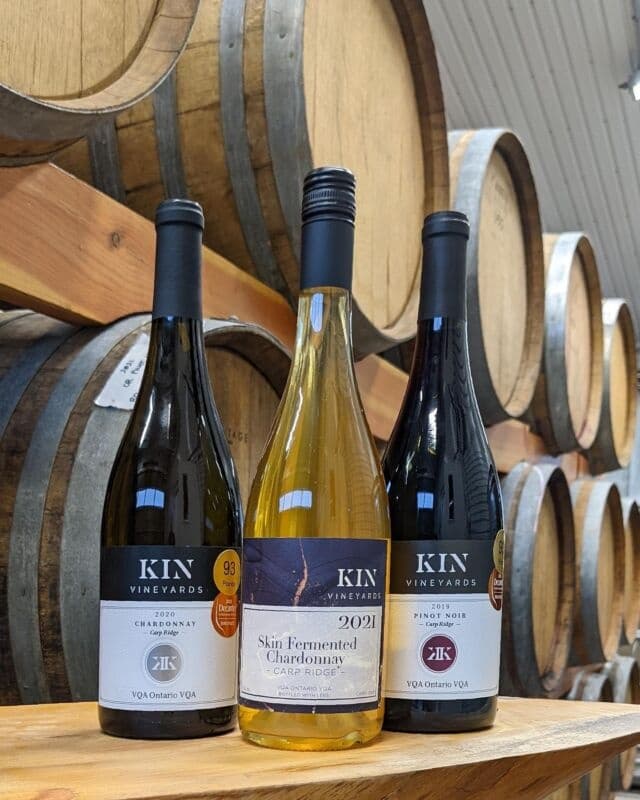 Wine bottles displayed in oak barrel cellar at winery tasting room