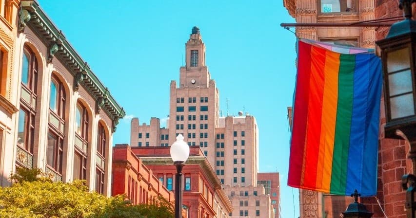 City street with large rainbow pride flag over historic downtown