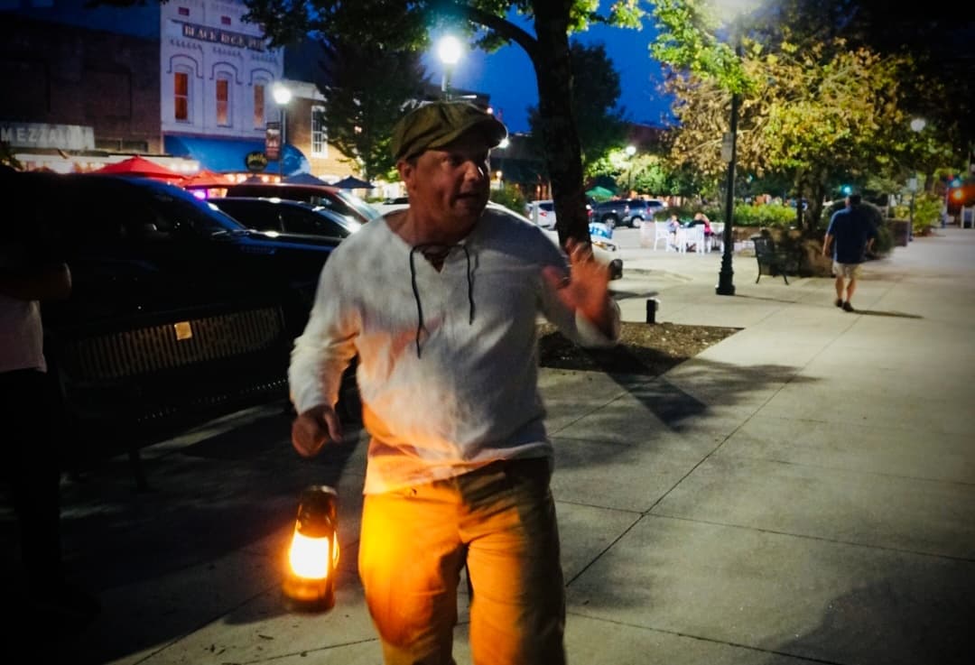 Guide with lantern leading nighttime ghost walking tour downtown