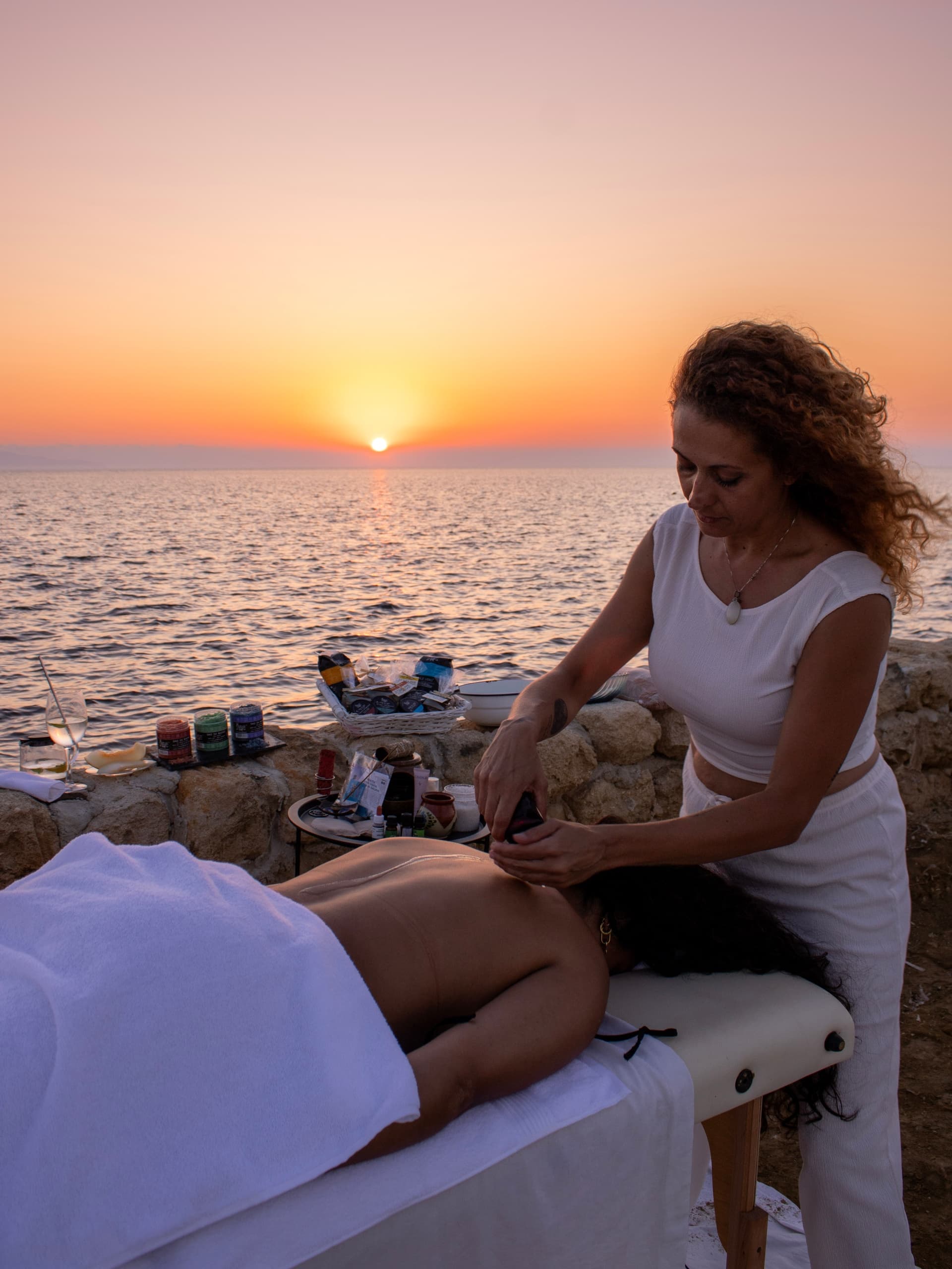 Outdoor seaside massage at sunset on rocky coast