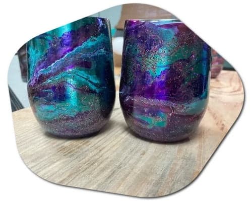 Pair of galaxy resin tumblers on wooden table in craft studio