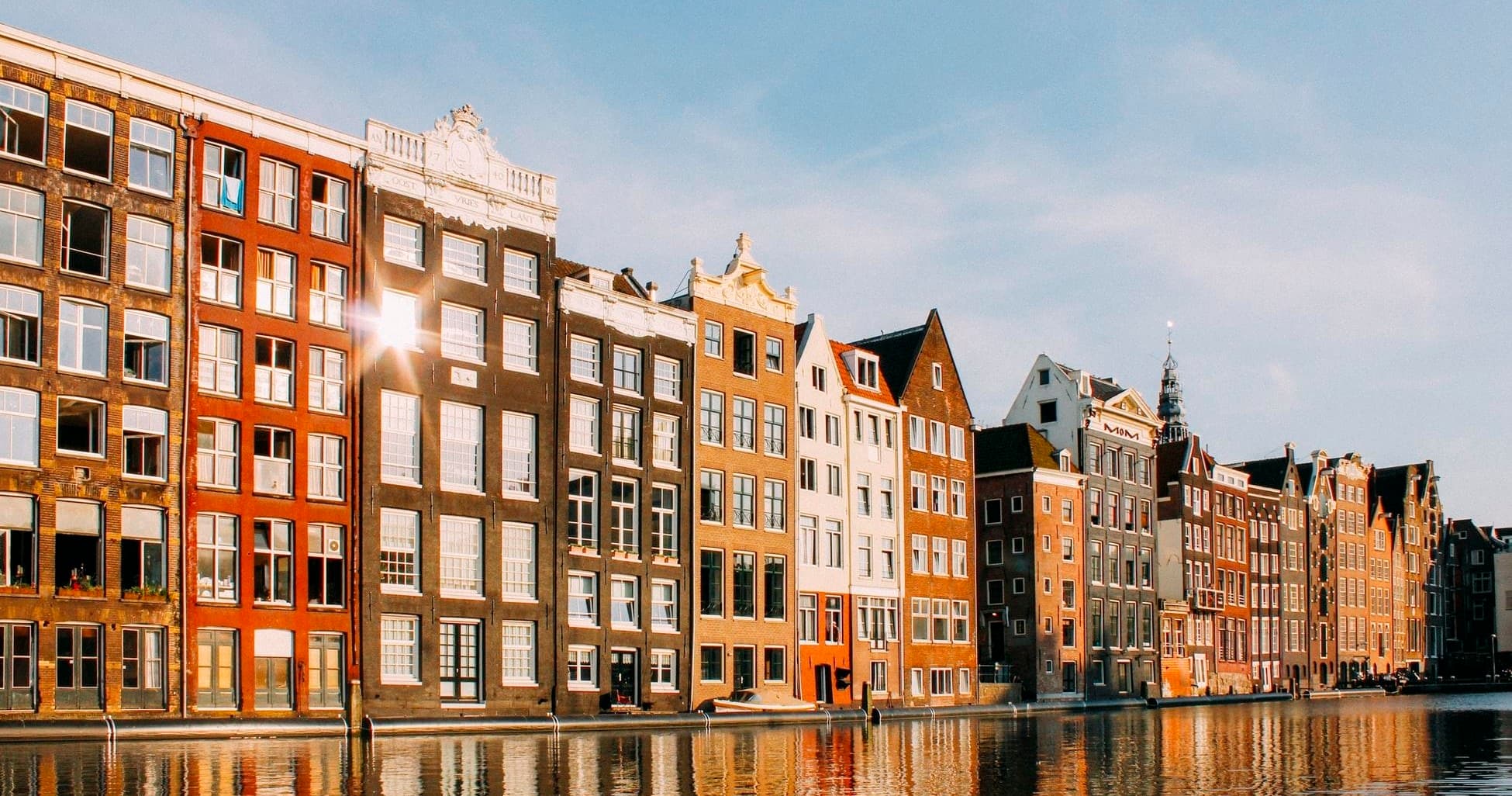 Historic canal houses reflected in water along Amsterdam waterfront