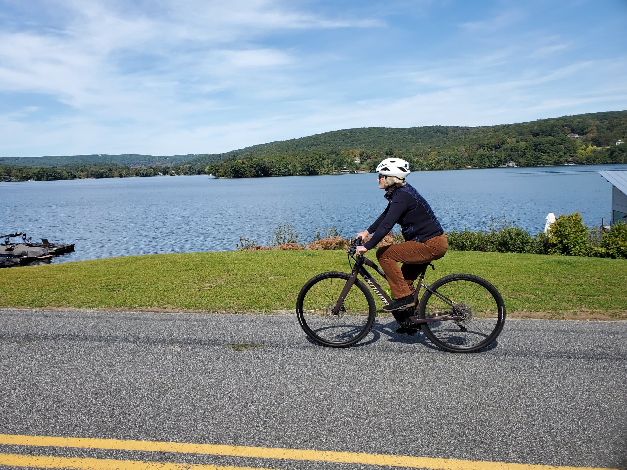 Cyclist riding past lakeside road with expansive water view