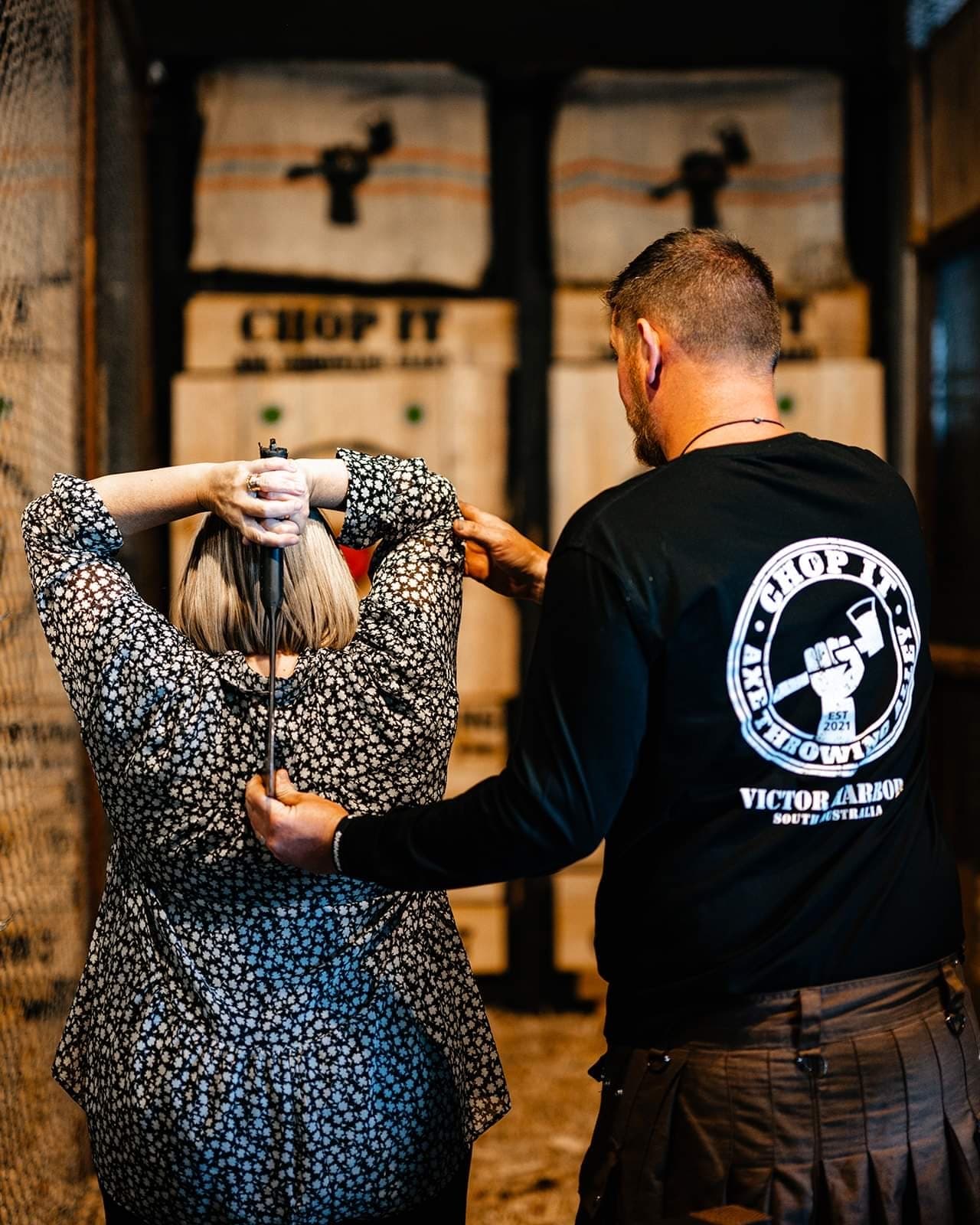 Instructor coaching participant at indoor axe throwing lane