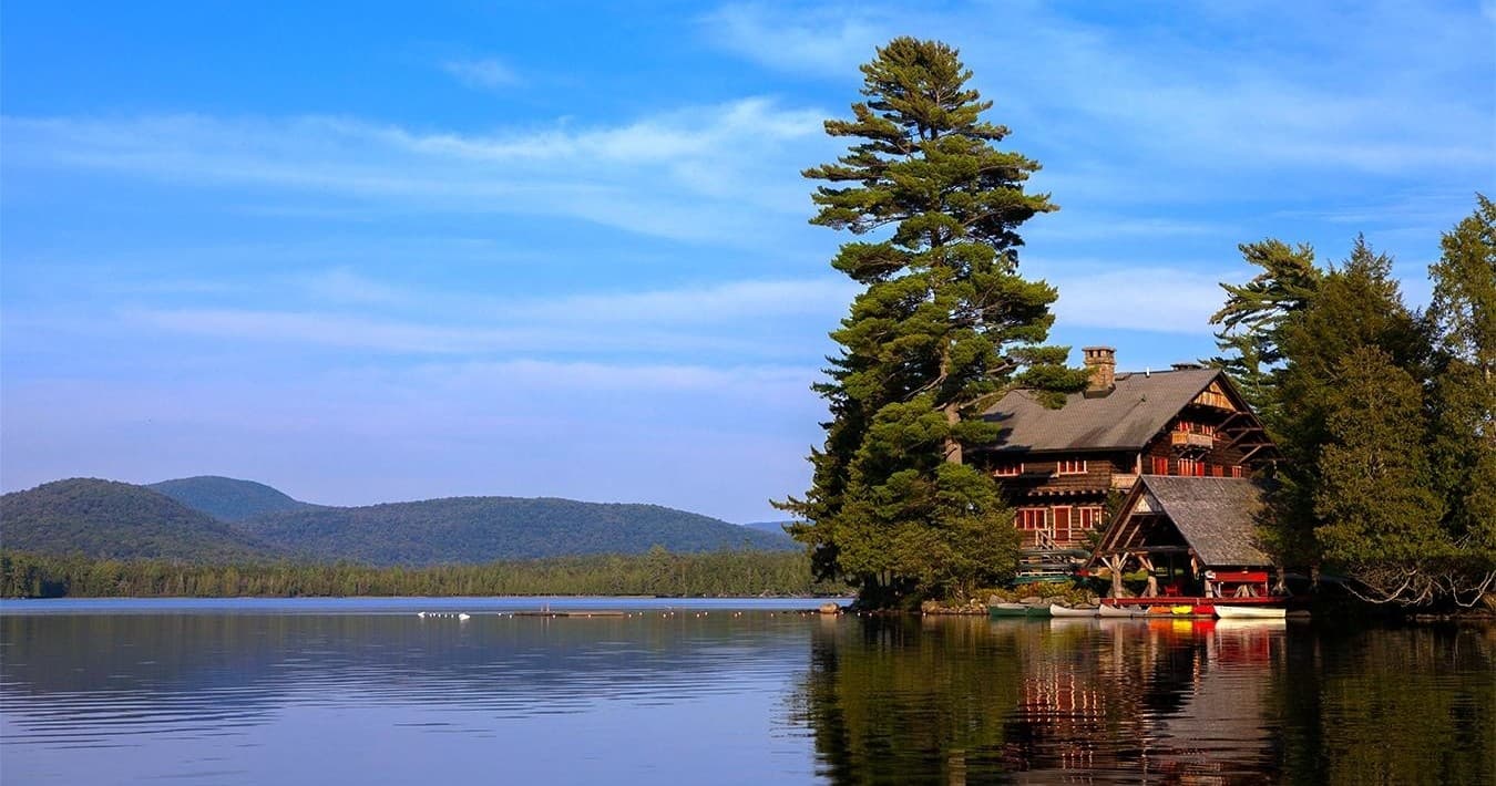 Lakeside great camp lodge reflected on calm mountain lake