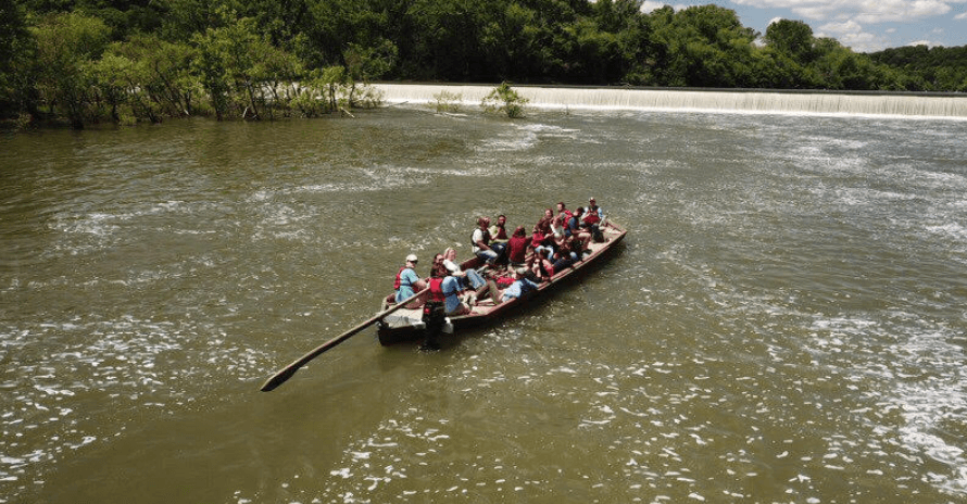 Dragon boat team paddling fast on wide scenic river