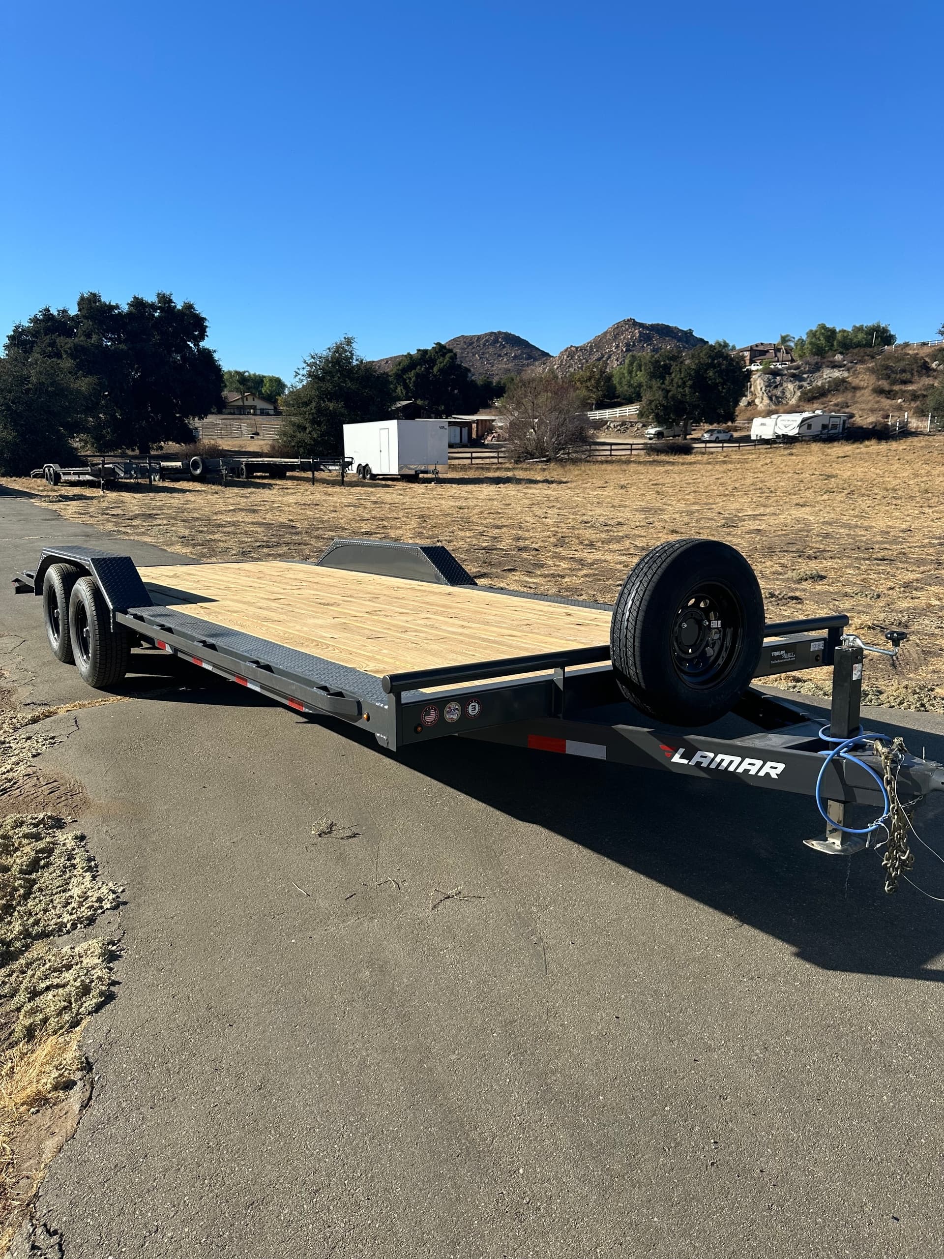 Dual-axle car hauler on paved road with open landscape