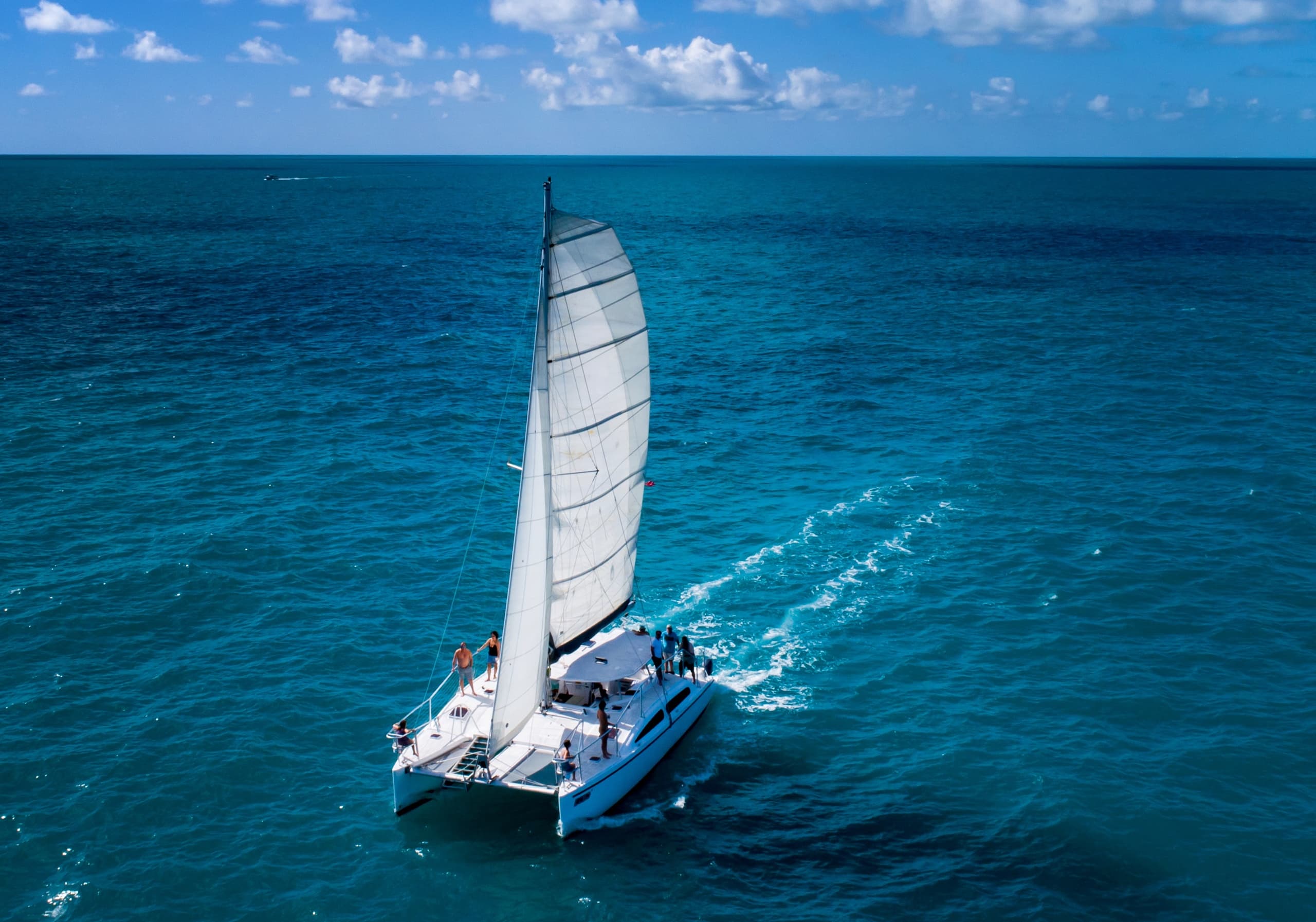 Sailboat catamaran cutting across clear open ocean water