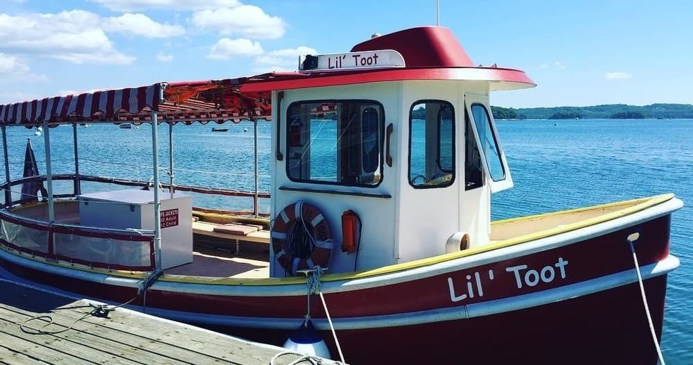 Red sightseeing launch moored at wooden dock in coastal harbor