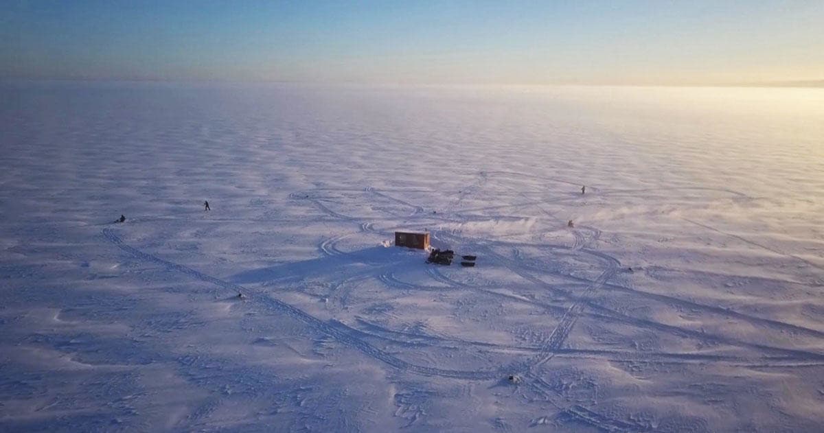 Snowy lake ice camp on frozen wilderness at sunrise