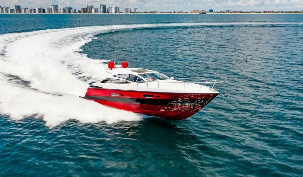 Red speedboat cruising on open ocean near coastal skyline