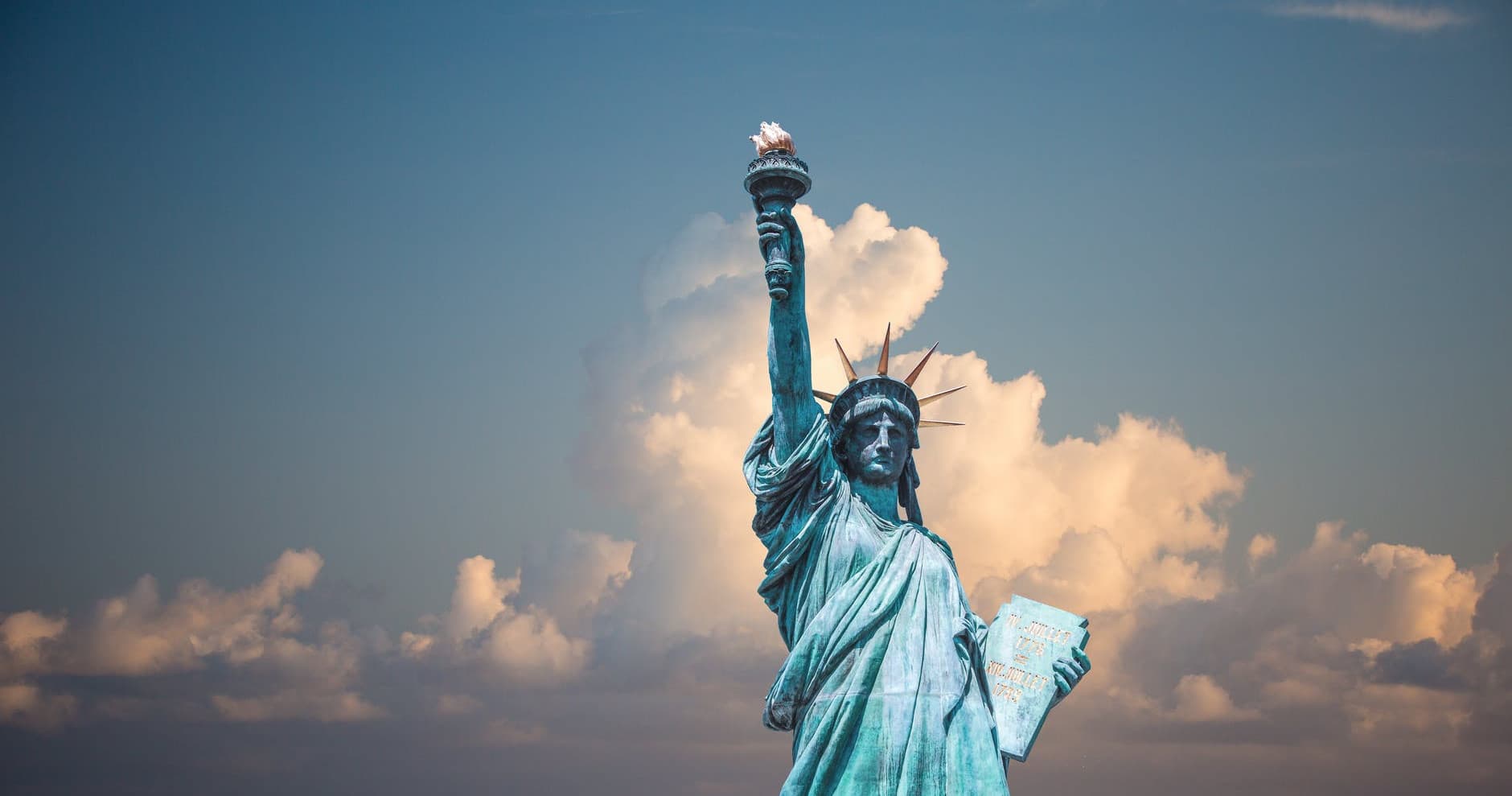 Statue of Liberty in New York Harbor with dramatic clouds