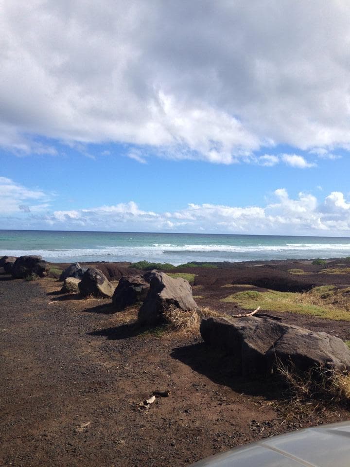 Rocky coastal shoreline with blue sky and distant ocean waves view
