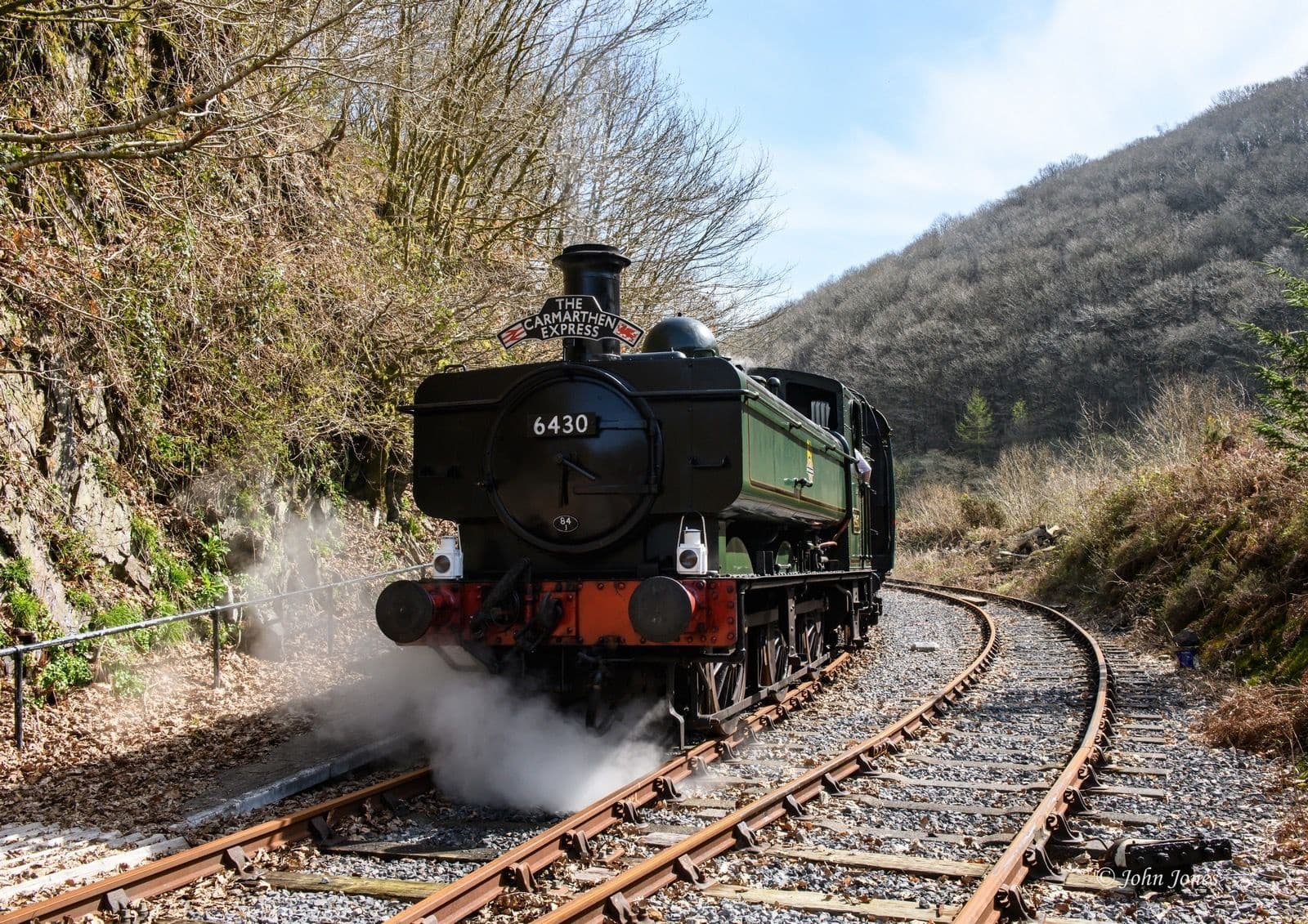 Steam locomotive on winding rural tracks in valley