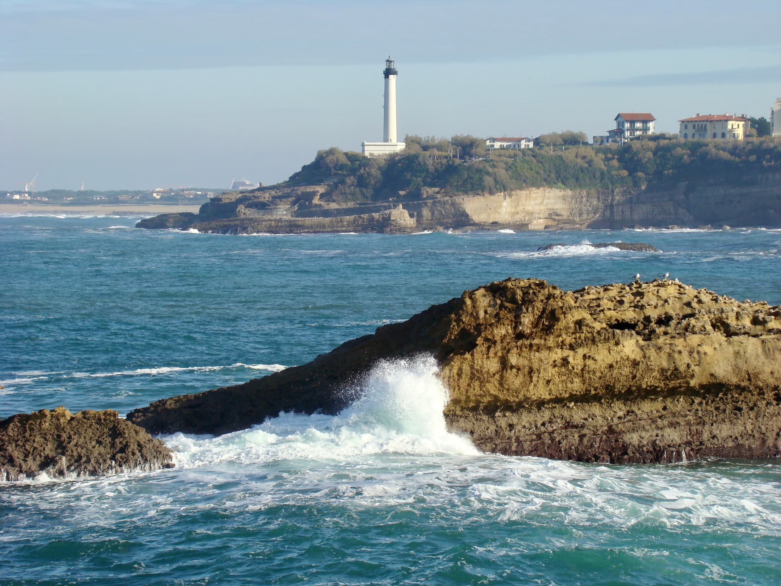 Lighthouse headland with crashing waves, coastal hiking viewpoint