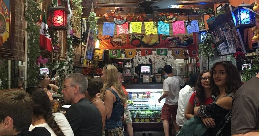 Crowded indoor market tasting session during food tour, colorful interior