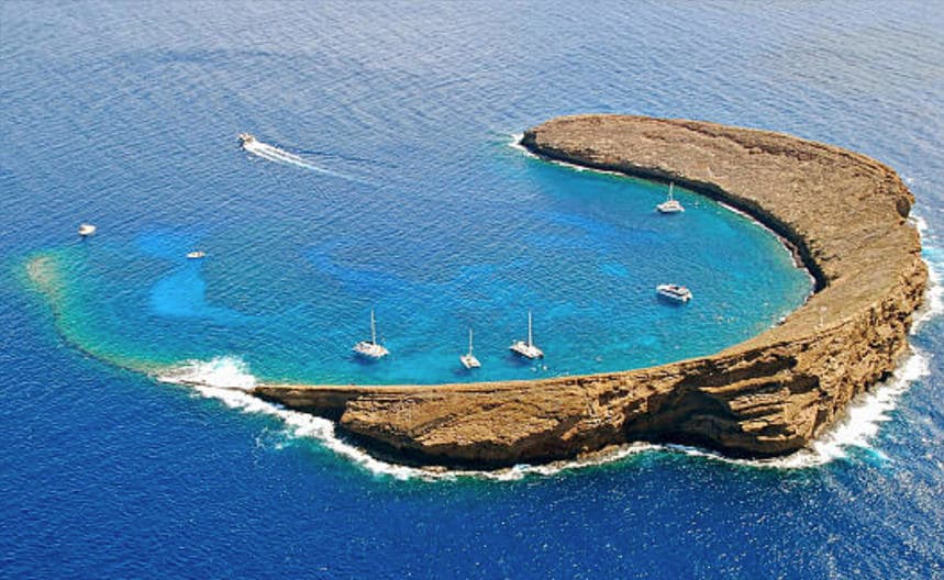 Aerial view of crescent bay with anchored boats near Maui coast