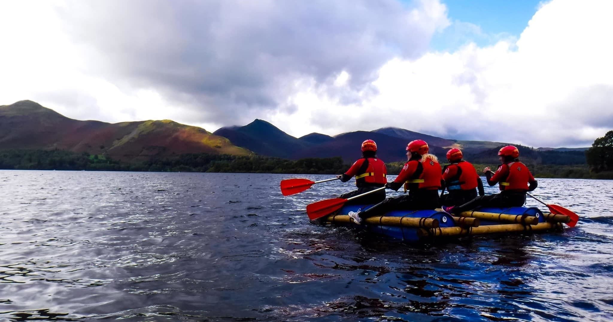 Rafting team paddling on open water with dramatic mountain views