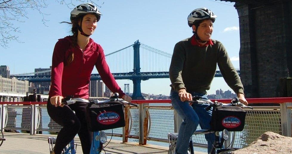 Two cyclists riding near Brooklyn Bridge waterfront in NYC