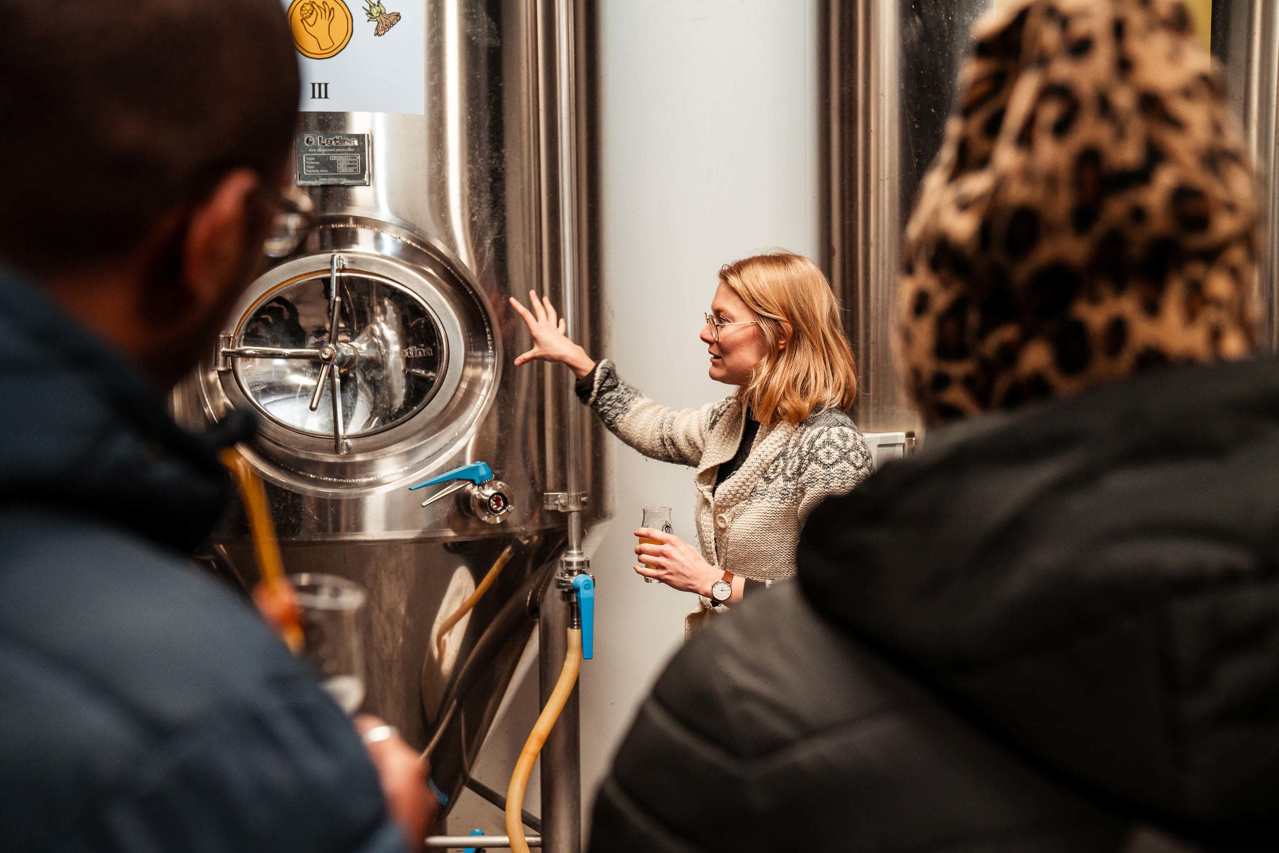 Guided brewery tour next to fermentation tanks in microbrewery
