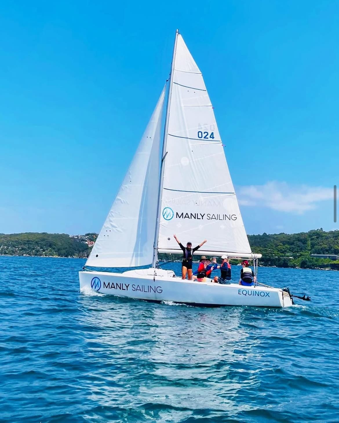 White sailboat cruising Manly waters on vibrant sunny day