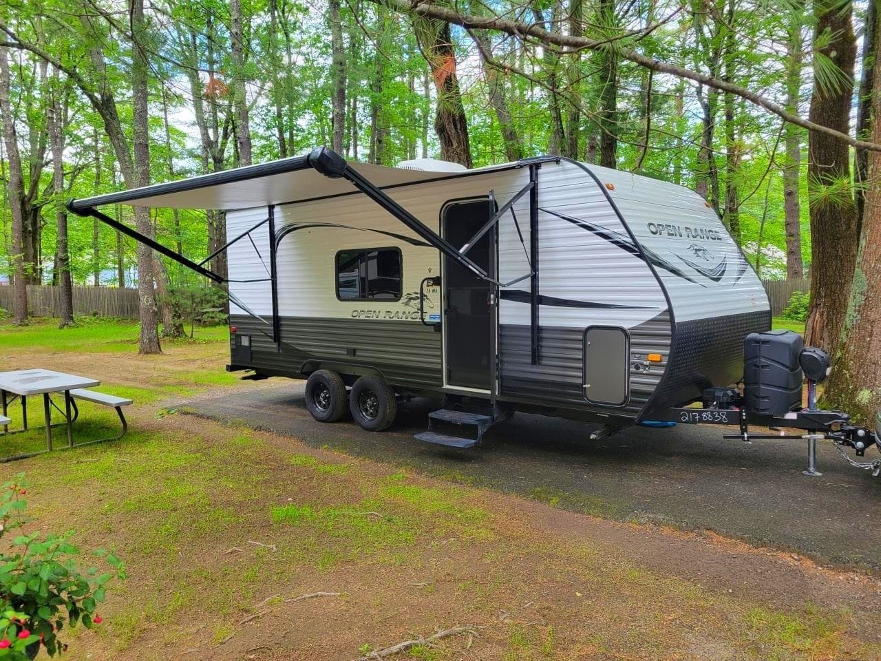 Camper trailer with awning at shaded forest campsite