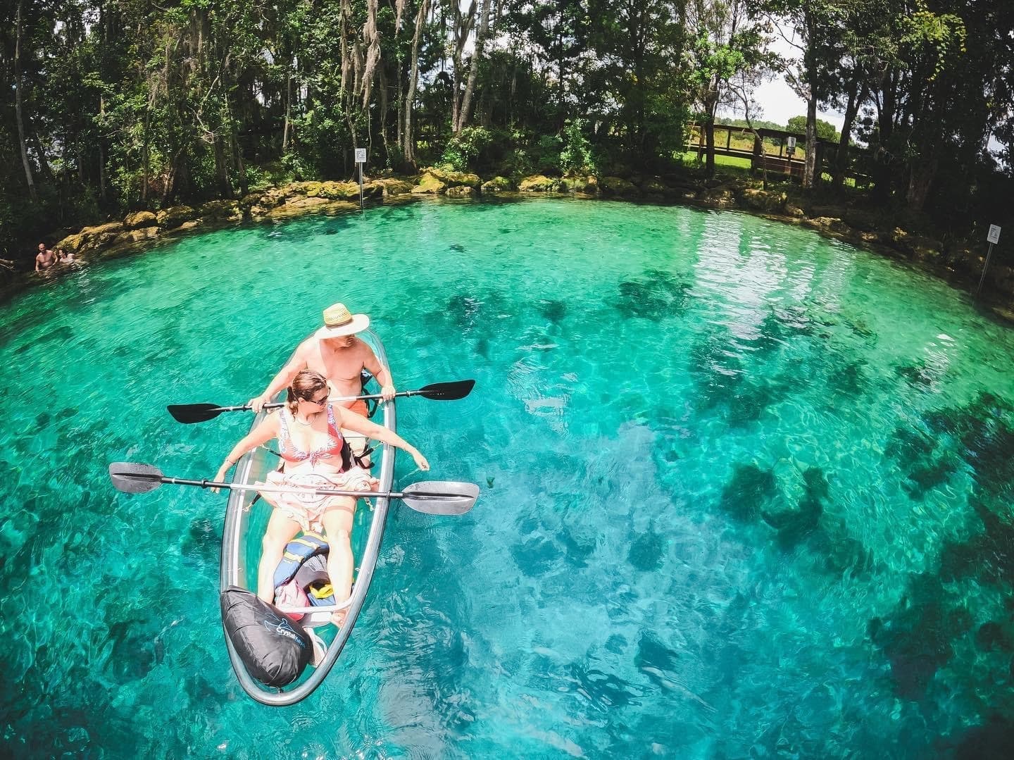 Aerial fisheye of tandem kayakers paddling over turquoise spring
