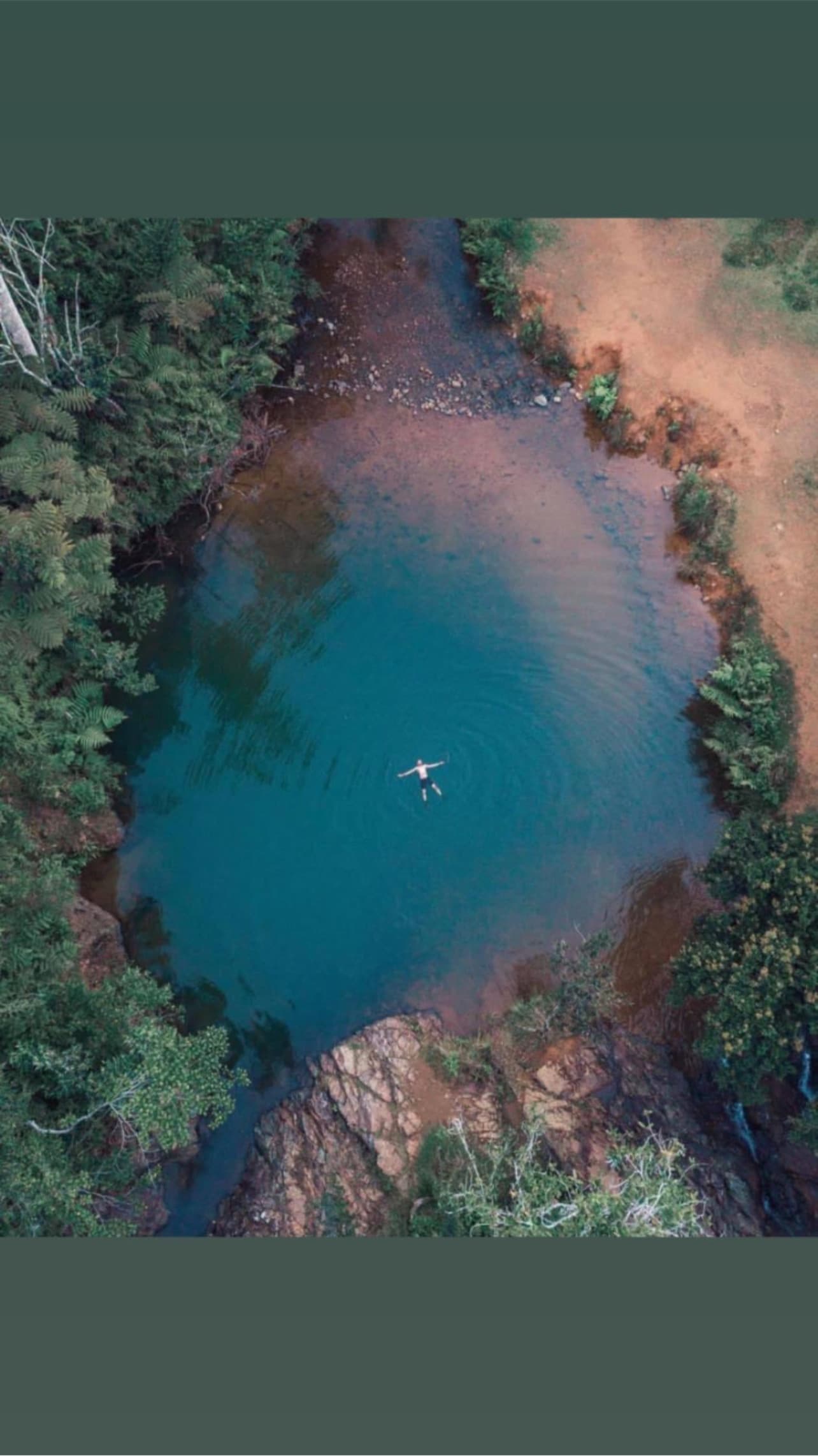 Aerial view of turquoise forest cenote surrounded by greenery