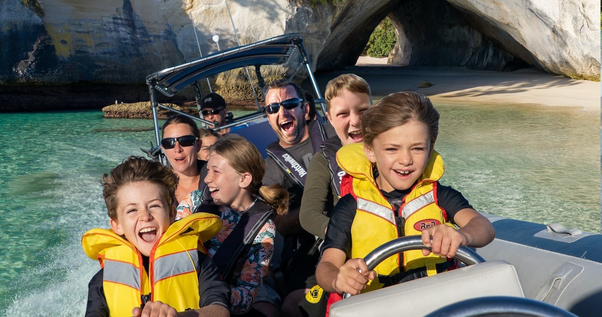 Family speedboat tour near coastal sea caves and beach