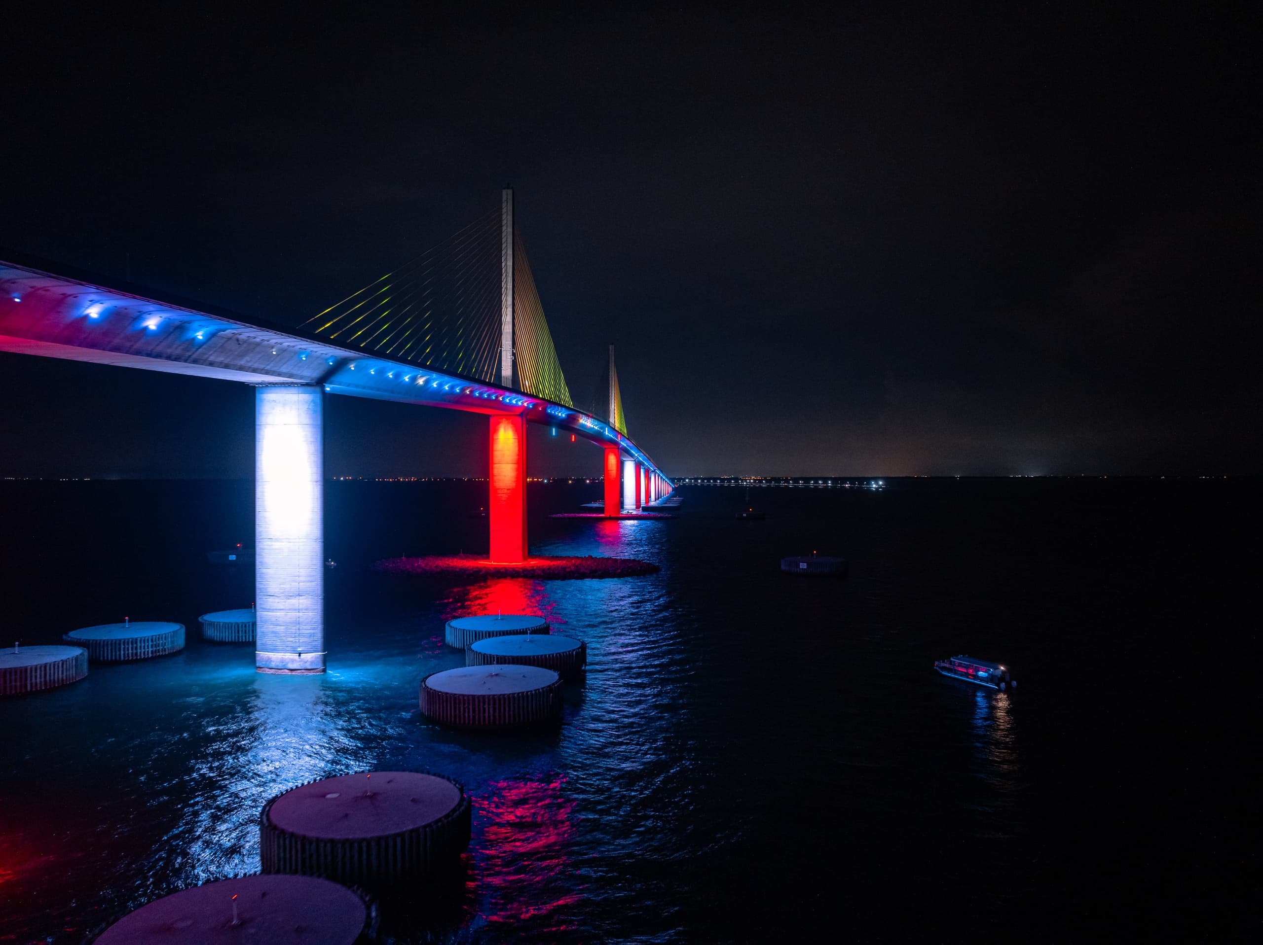 Illuminated Sunshine Skyway Bridge at night reflecting over bay
