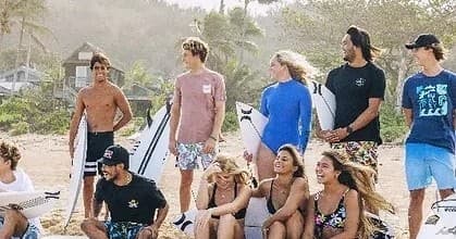 Surf students and instructors posing on sandy Hawaiian beach