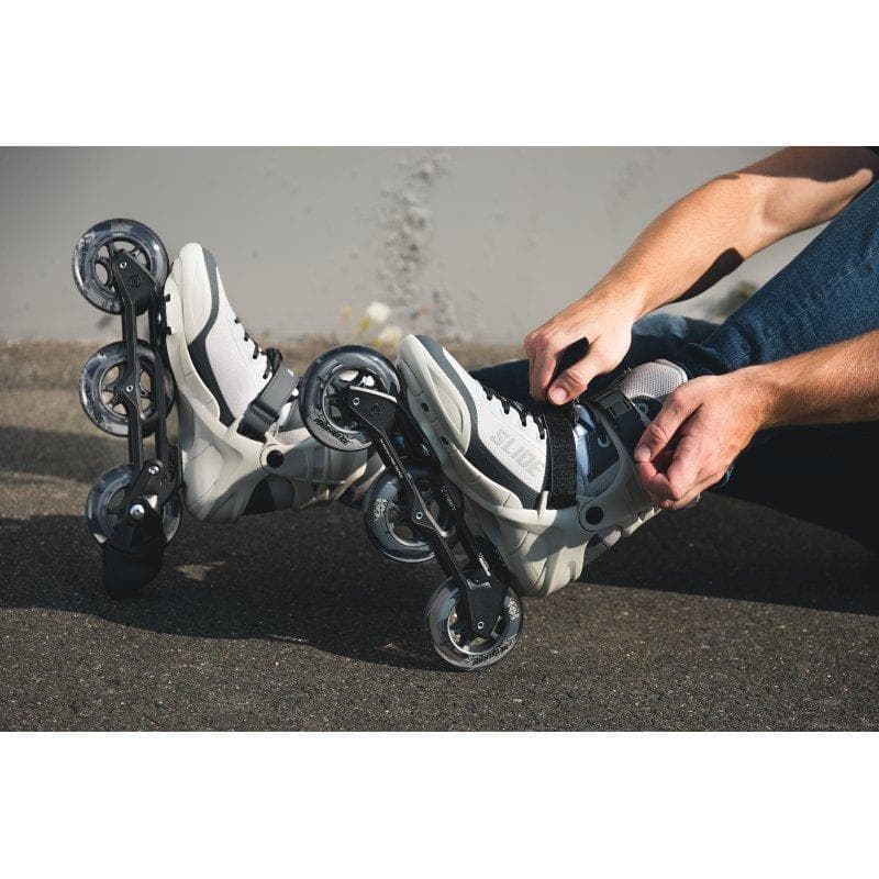 Person tightening inline skates on pavement before outdoor ride