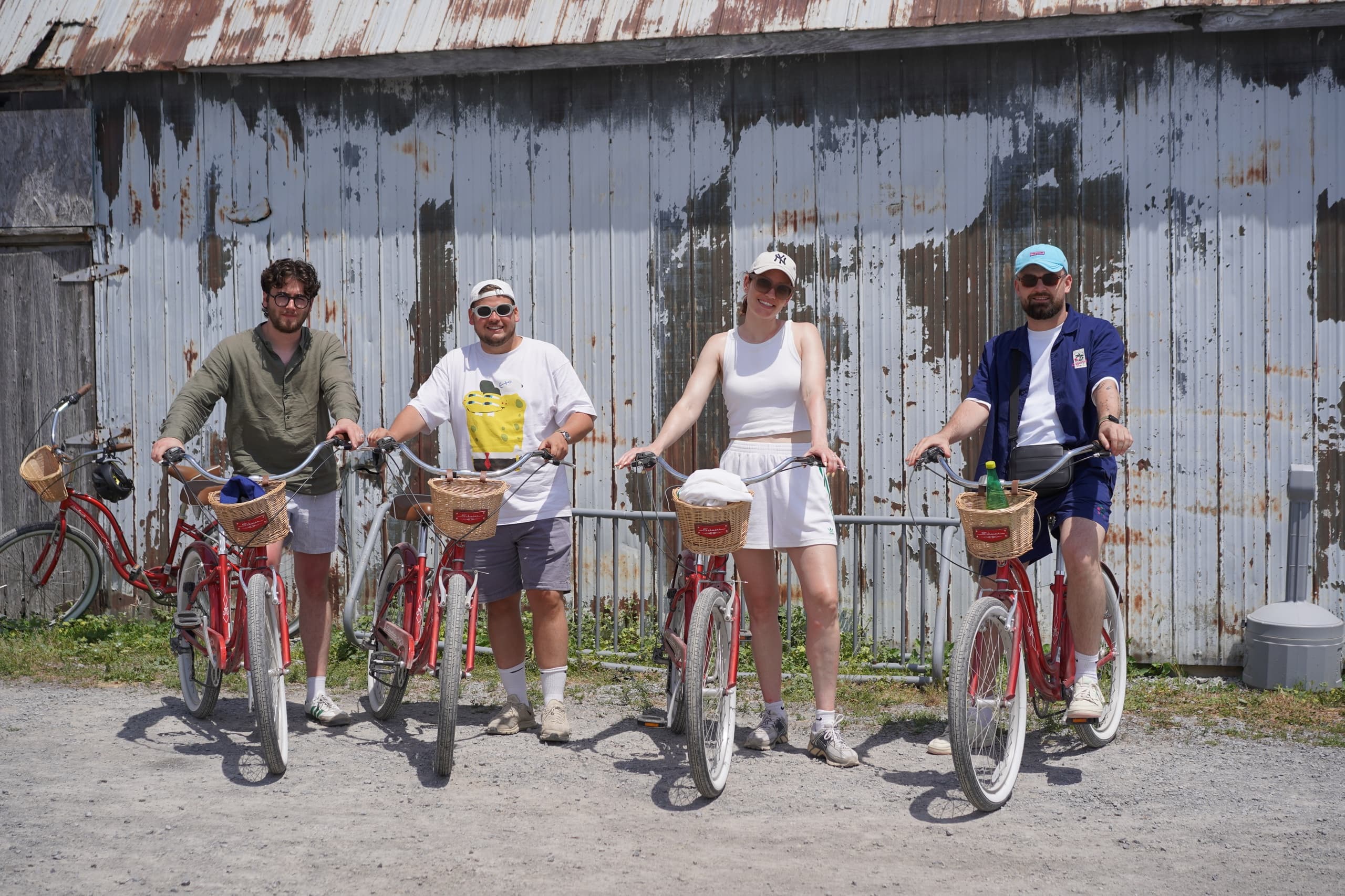Group of cyclists posing with red bikes by rustic barn
