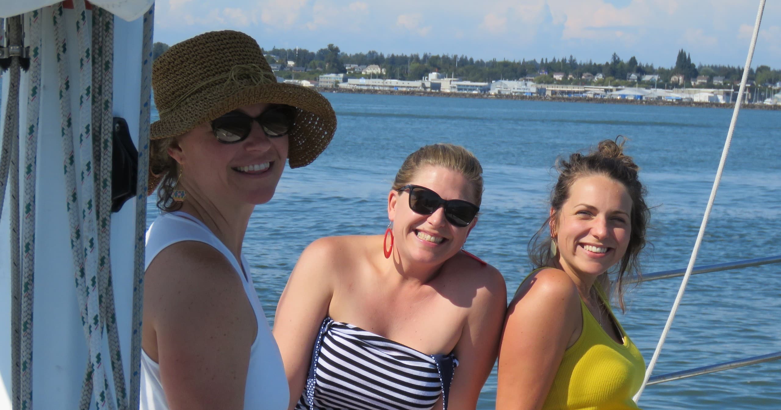 Friends relaxing on sailboat deck with coastal backdrop