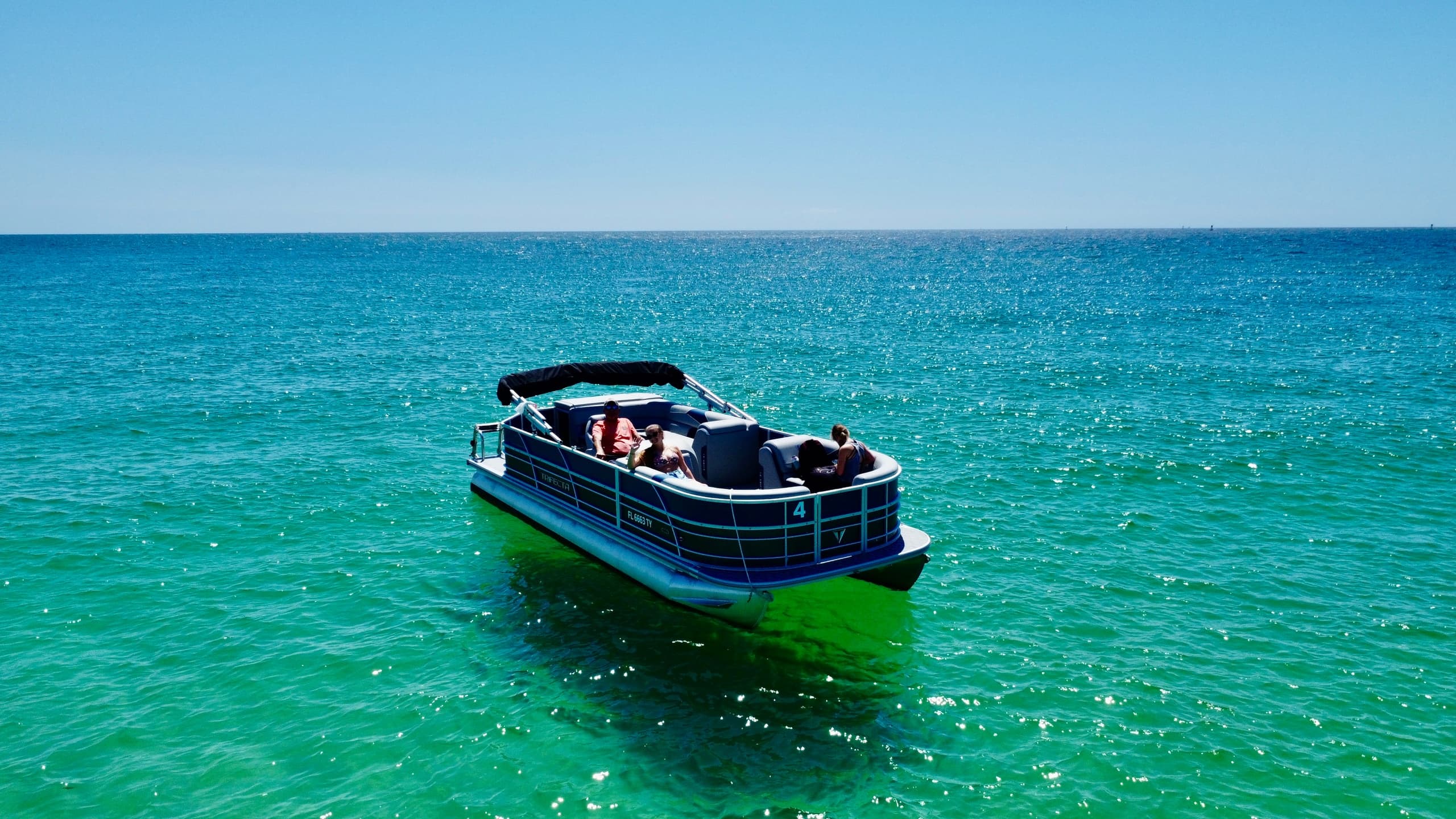 Pontoon boat cruising turquoise Gulf waters near shore